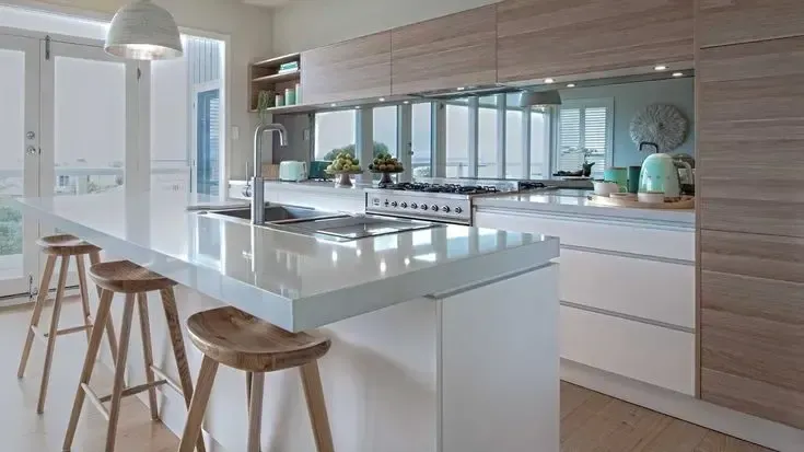 Bright modern kitchen with white island and wooden stools